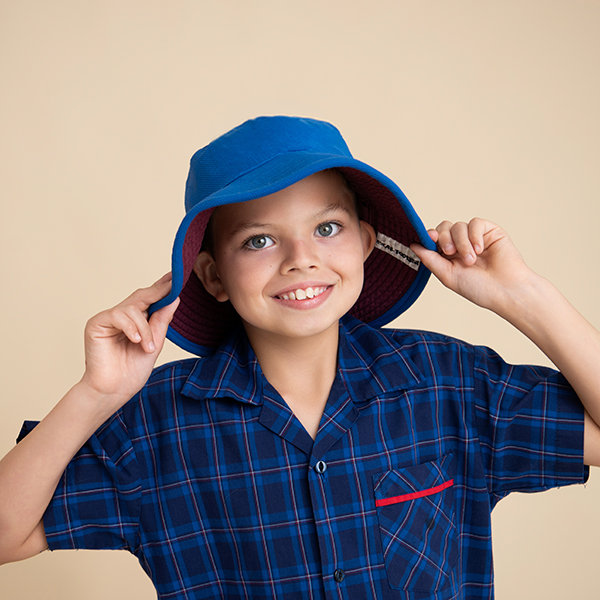 School boy holding onto hat